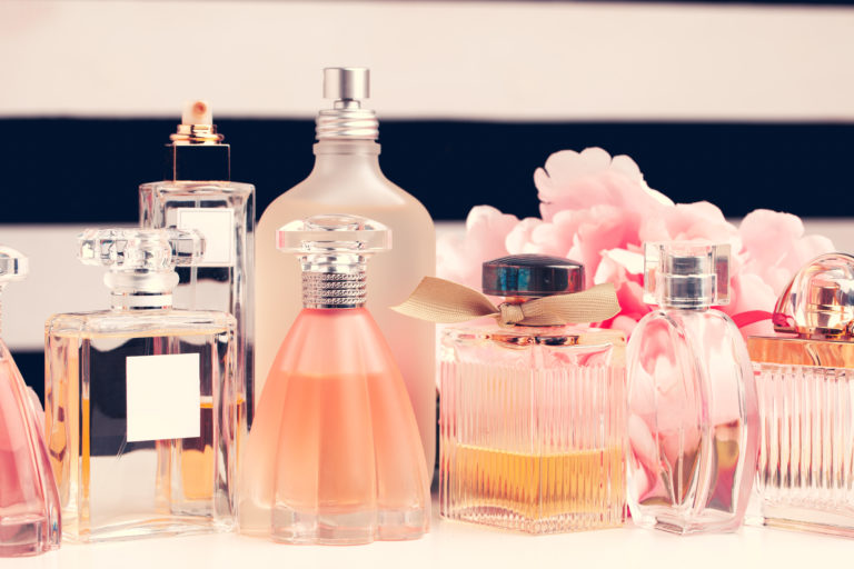 Bottles of perfume with flowers on white background